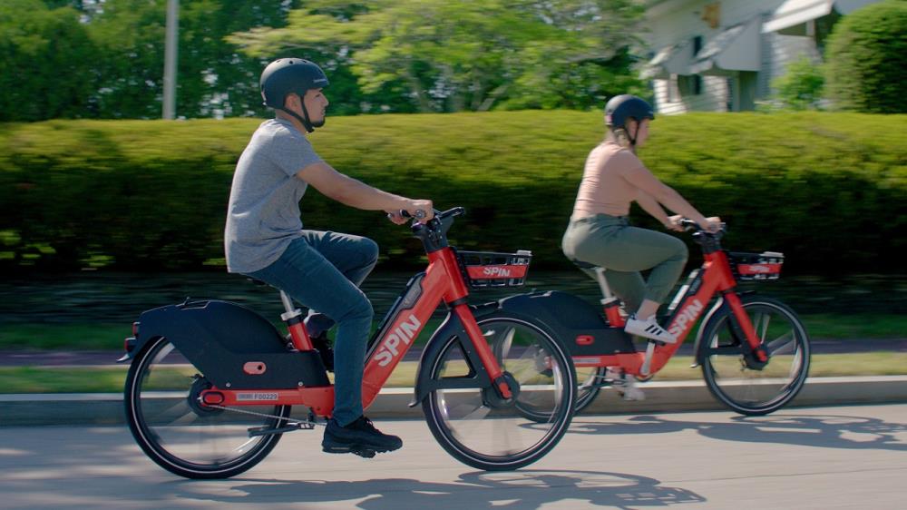 Spin - 2 people biking on street (widescreen)