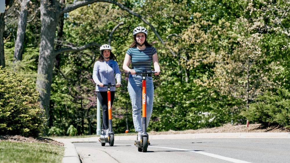 Two people on escooters helmets (widescreen)