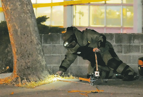 explosive ordnance officer in full protective uniform working at the base of a tree